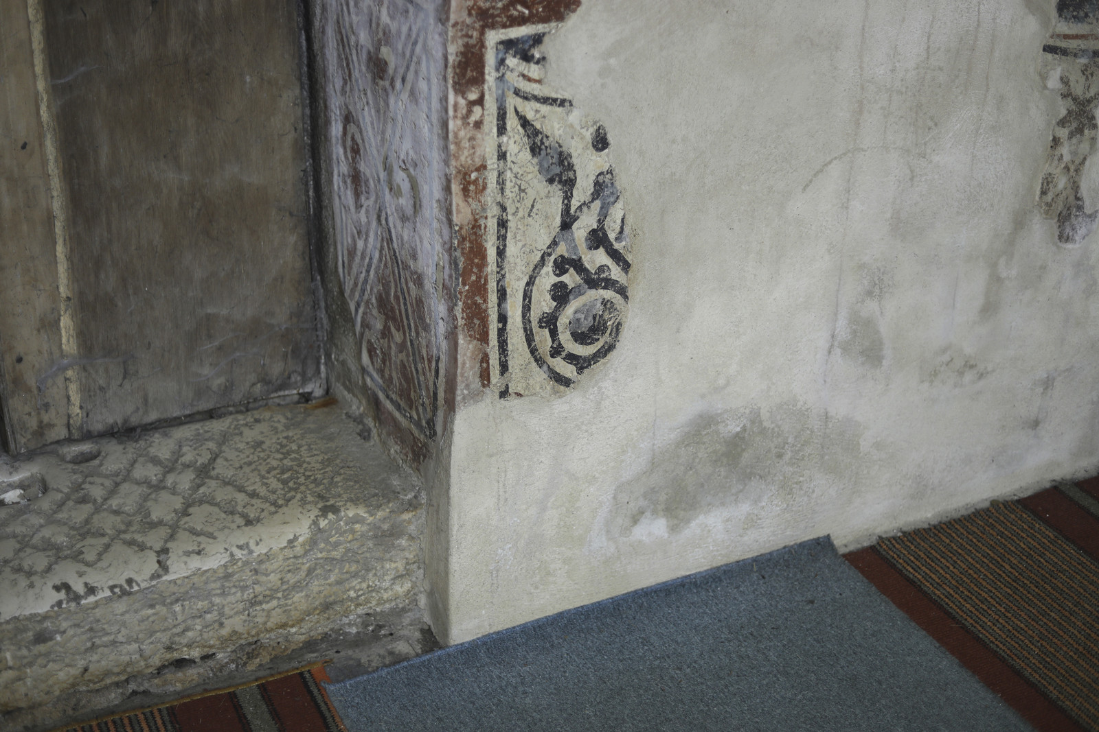 Stone doorstep of the west enrance into the nave and segment of the painted dado