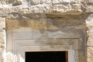 Камена греда са  розетама и остацима бојеног слоја изнад надвратника портала цркве